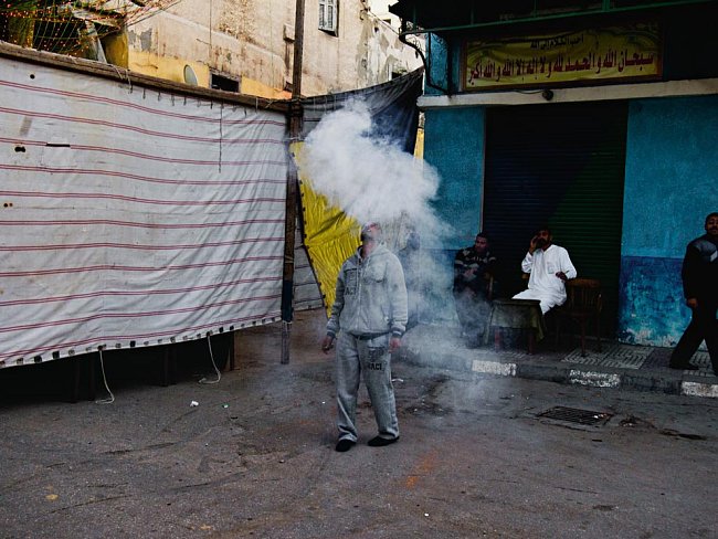 Zatímco demonstranti a bezpečnostní síly bojují o osud Egypta, život pokračuje v obvyklém rytmu. Muž v oblaku kouře po malé rachejtli vypálené na oslavu svatby v Alexandrii.