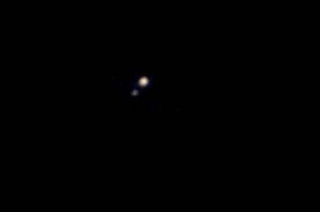 Tento snímek Pluta a Charonu pořídila kosmická loď New Horizons 9. dubna 2015 ze vzdálenosti zhruba 115 milionů kilometrů. Byla to první barevná fotografie systému Pluta pořízená blížící se kosmickou lodí.