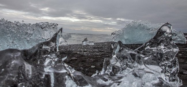 Severní ledový oceán poblíž ledovce Breiðamerkurjökull, ze kterého se odtrhávají ledové kry, sesunují se na vodní hladinu jezera Jökulsárlón a směřují k moři, kde je vlny vyvrhují zpět na pevninu. 