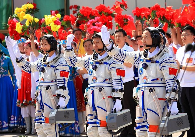 Tři čínští astronauté (zleva: Liu Yang, Liu Wang a Jing Haipeng) před vesmírnou cestou zdraví před odletem 16. června 2012. 