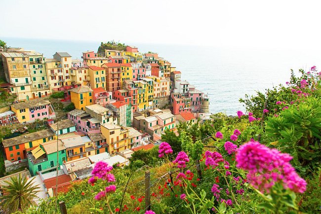 Italské městečko Manarola se proslavilo zástavbou na vysoké terasovité skále tyčící se nad mořem. Díky barevným fasádám svítí do daleka.