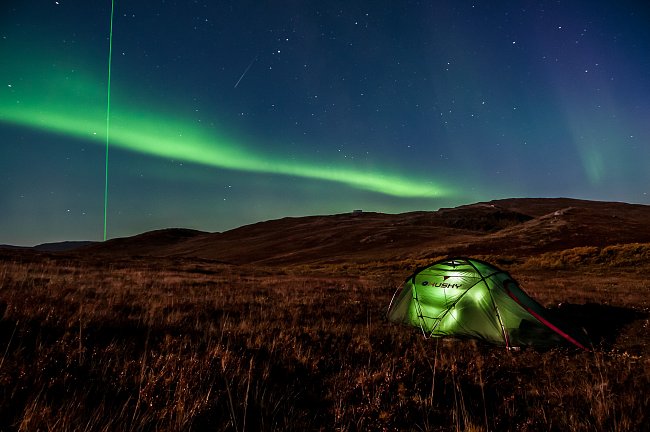 Stan stojící nedaleko mezinárodního letiště Kangerlussuaq. Vedle polární záře je možné si všimnout laserového paprsku mířícího ze zdejší vědecké stanice Kelly Ville do ionosféry. Pomocí tohoto laseru 