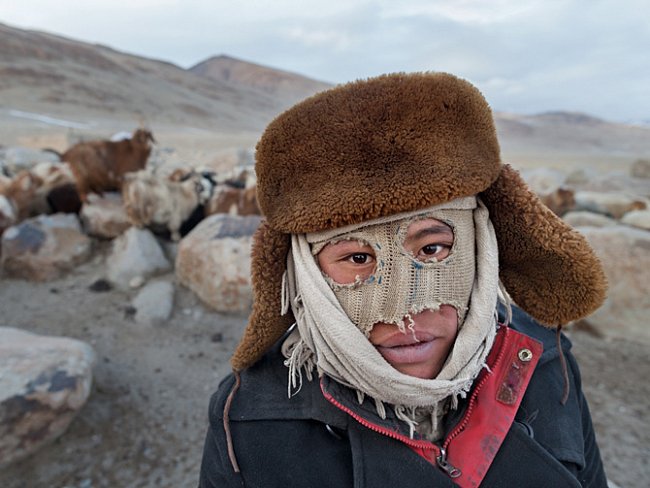Mladý pastevec má na obličeji improvizovanou masku, která ho chrání před extrémním zimním chladem.