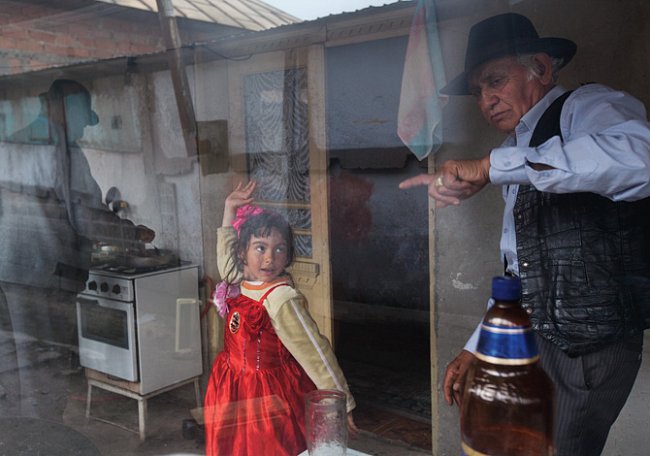 Život mimo rezidenční čtvrť Buzescu: kuchyně chudé romské rodiny slouží šestileté Iasmině Iancuové, která se v ní točí pro svého dědečka Iona, jenž ji vychovává, jako taneční sál. Iasminina matka prac