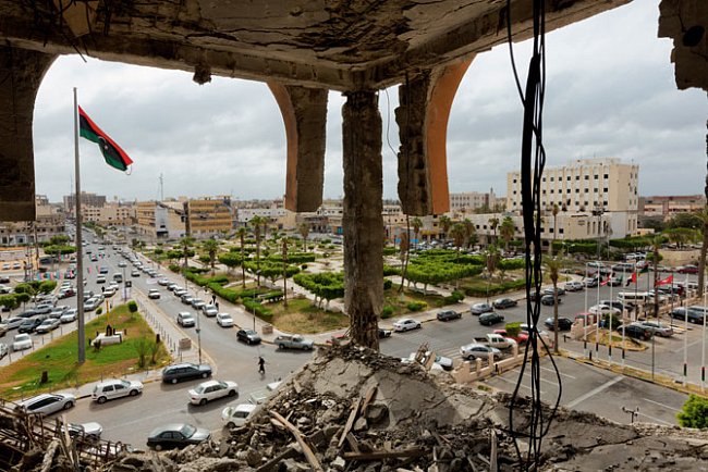 Na tom, co zbylo z Banky pro obchod a rozvoj v az-Záwiji, zničené raketovou palbou za bojů mezi Kaddáfího věrnými a milicemi v březnu 2011, visí volně dráty. 