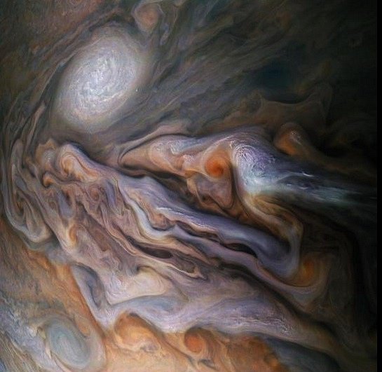 Velkolepé mraky víří jako inkoust v Jupiterově Severním mírném pásu, zde pozorovaném sondou NASA Juno. Pohled obsahuje bělavé „vystupující“ mraky a bílý ovál, což je jistý druh anticyklonové bouře, která je menším příbuzným Jupiterovy Velké rudé skvrny.