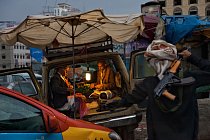 Jakýsi muž prochází kolem s kalašnikovem v ruce, když Muhammad Alí Džubabí (vlevo) a jeho syn připravují na bazaru v San‘á chomáče kátu, oblíbených povzbuzujících listů. 