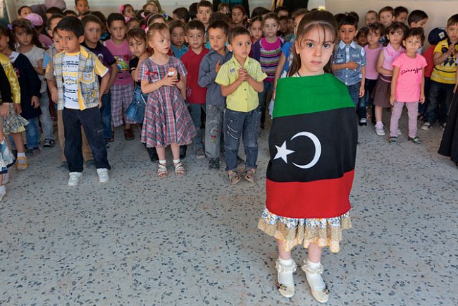 Pětiletá Fátima Šatwánová, zahalená do tříbarevné vlajky nezávislé Libye, na školním shromáždění v Misrátě. 