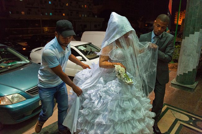 Nevěstu ozdobenou krajkami a dekoračními motivy namalovanými hennou na rukou přivádějí do hotelu v Benghází. 