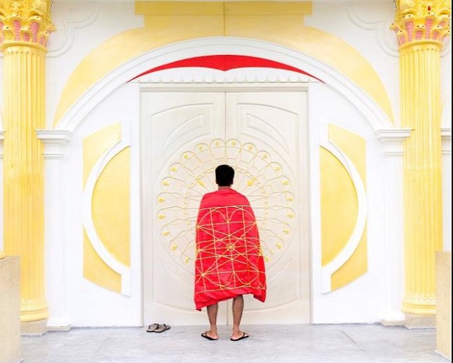 Vietnam: Son Bui stojí u svého hotelu Palace of Revelation (Palác Zjevení), který je celý založený na knize Zjevení. Navrhl vlastní „světovou vlajku míru“ (zobrazena nahoře), která představuje jednu lidskou rodinu.