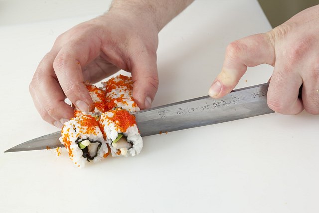 6. Sushi opatrně pevně zarolujte – dávejte si ale pozor, abyste náplň po stranách nevytlačili ven. Namočte nůž a rozkrojte na šest porcí.