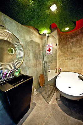 Koupelně dominuje beton, který zjemňuje zelená barva na stropě.