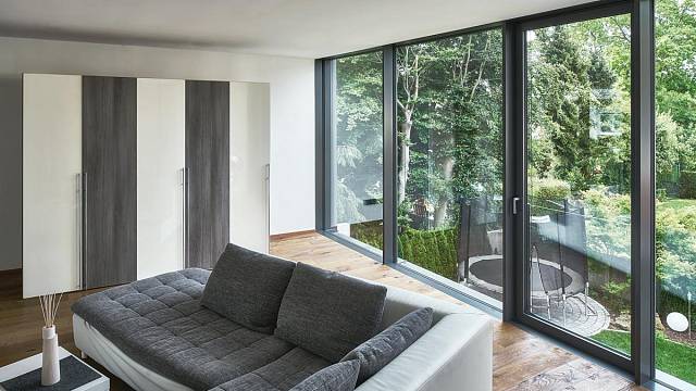 Obývací prostor v horním patře: Prosklené elementy na výšku místnosti, z nichž jeden lze otevírat, umožňují maximální přísun světla a výhled do zahrady