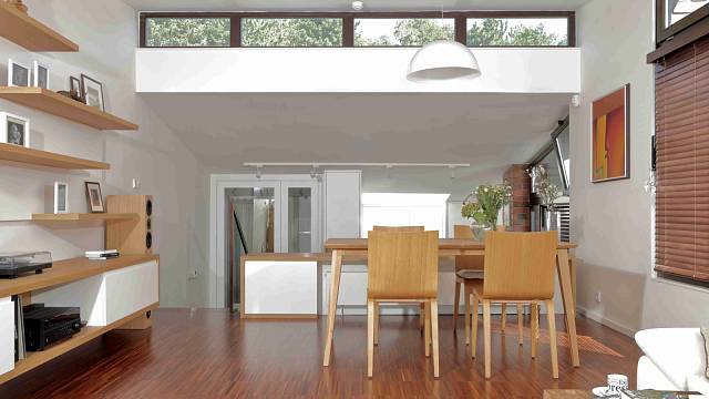 Obývací pokoj je hodně světlý i díky původnímu pásovému prosklení. Na rozhraní pokoje a kuchyně je dlouhá nízká komoda, která kryje radiátory a funguje i jako zábradlí.