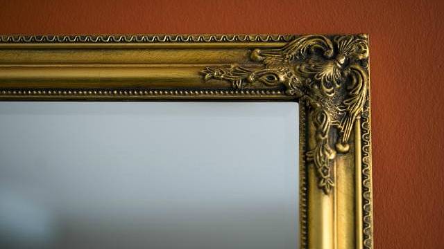 Zrcadlo ve zlatém rámu je vhodným doplňkem