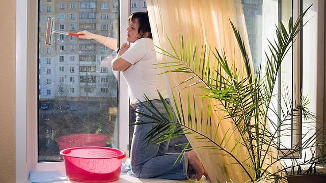 Žena hazardující při mytí okna