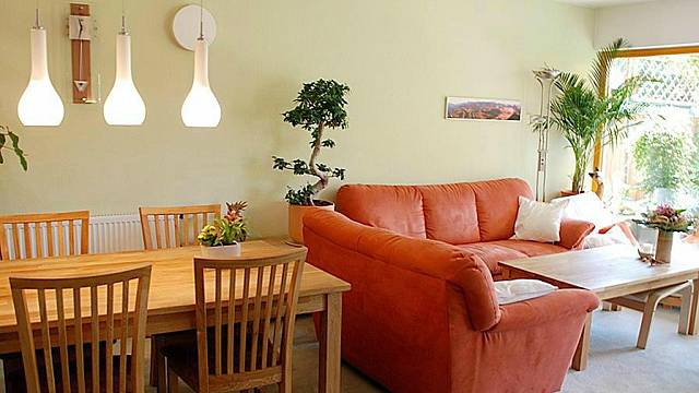Obývací pokoj je spojený s kuchyní a jídelním prostorem. Dominantou obytného porstoru je červená rohová sedačka s velkým jídelním stolem z masivu. 
