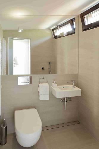 Koupelny pracují s nadčasovou kombinací bílé a šedé.