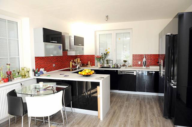 Kuchyně je zařízena moderně v černo-červených barvách, které doplňuje barva bílá. 