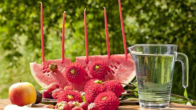 Chystáte letní ovocné osvěžení pro děti? Nalákejte je na melounový svícen. Do melounové výseče zapíchejte tenké dlouhé svíčky a dozdobte květy jiřinek. Protože je meloun samá voda, květy vydrží čerstvé velmi dlouho.