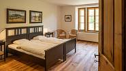 V ložnici majitelů je postel asymetricky umístěna v rohu, ložnice pro hosty v patře jsou vybaveny stylovým nábytkem.