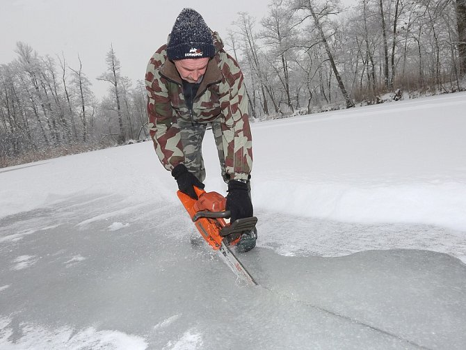 OSM CENTIMETRŮ byl v sobotu ráno silný led na Doksanském rybníku u Ohře. Rybáři proto vyrazili na zamrzlou hladinu se sekerami a pilami, aby do ledu udělali otvory.
