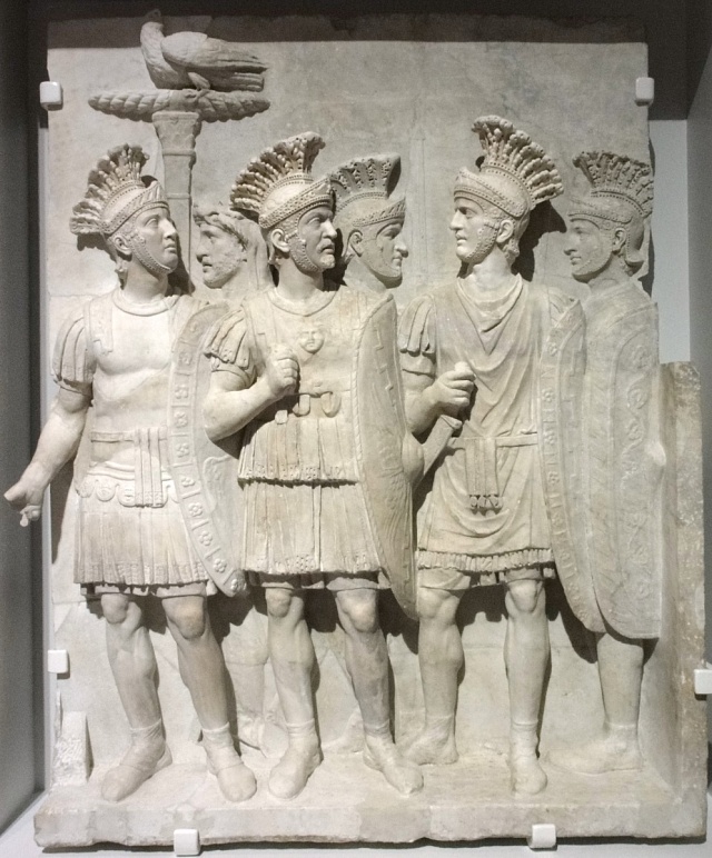 Reliéf pretoriánů s akvilou svírající v pařátech blesk, což je odkaz na římskou podobu Jupitera.