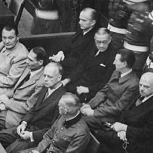 Nacističtí prominenti před soudem v Norimberku: přední řada zleva Göring, Hess, Ribbentrop a Keitel, zadní řada zleva Dönitz, Raeder, Schirach a Sauckel
