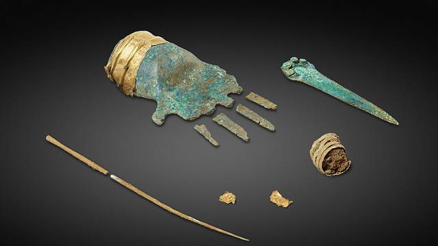 bronzová ruka a další artefakty nalezené v hrobě.