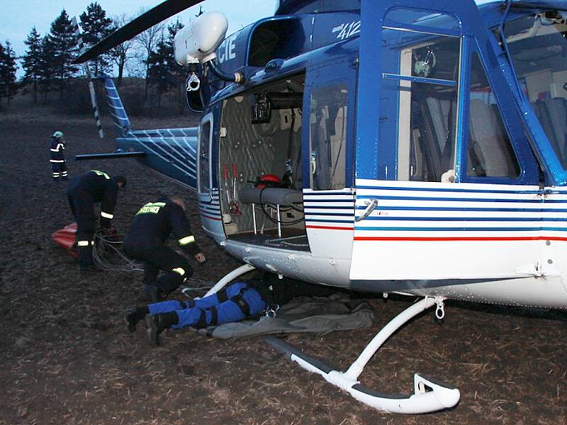 Na pomoc přiletěl i policejní vrtulník. Právě se pod něj upevňuje vak na vodu