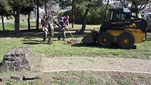 Pracovníci Technické správy města Žatec uklízejí okolí podstavce pomníku v parčíku u žateckého západního vlakového nádraží