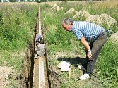 Petr Holodňák sleduje práci archeologů ve výkopu pro přeložku plynovodu na východním okraji Žatce. 