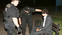 Strážníci promlouvají s opilým mladíkem, který se ještě v obleku potácel ulicí a pak polehával na lavičce.