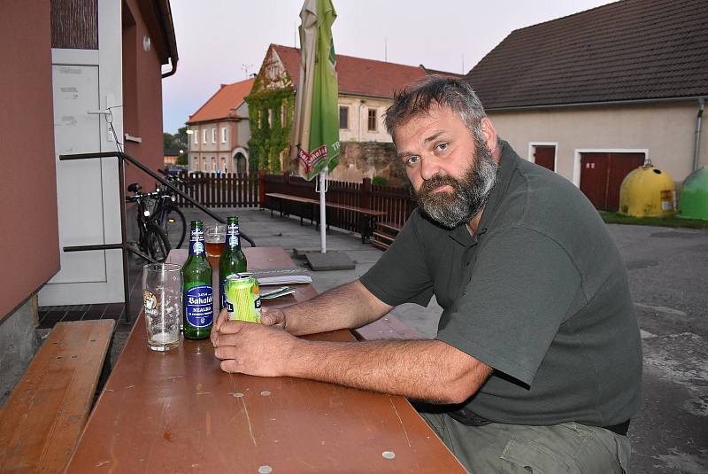 Daniel Pitek sedí u venkovního stolu hospody na návsi v Blatně na Podbořansku. Letos zavřela.
