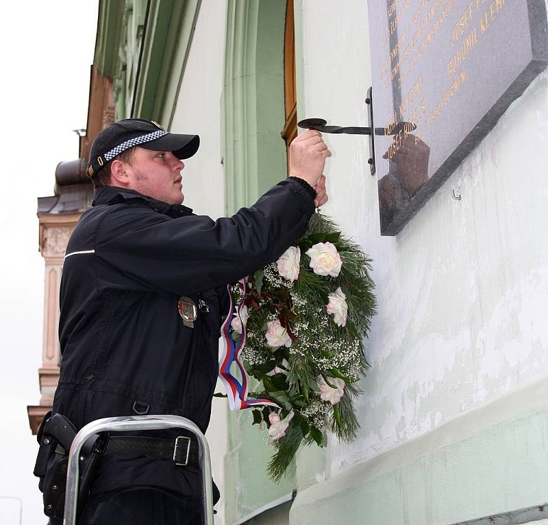 Strážník věší květiny k pamětní desce na lounské sokolovně