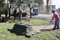 Pracovníci Technické správy města Žatec uklízejí okolí podstavce pomníku v parčíku u žateckého západního vlakového nádraží