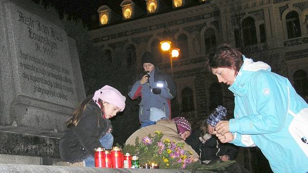 Lidé kladou svíčky k pomníku J. Husa na lounském centrálním náměstí.