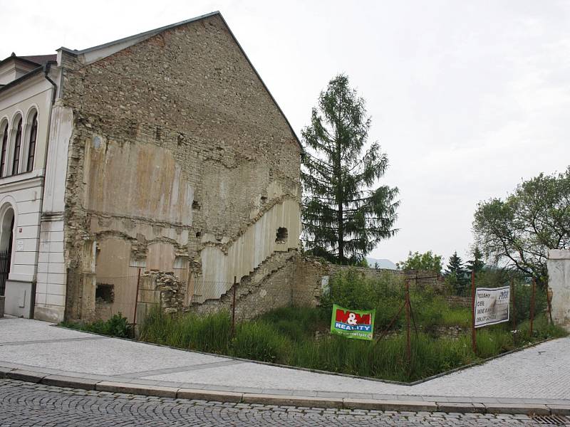 Takto vypadalo místo vedle synagogy mnoho let. Zbytky původní stavby zarůstající vegetací. Snímek z června 2014. Soukromý majitel tehdy do sanace prostoru neinvestoval.