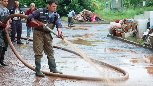 Dobrovolní hasiči z Krásného Dvora uklízejí po bleskové povodni v Kryrech. Do městečka přijeli rovnou z jiných povodní, pomáhali na Litoměřicku.