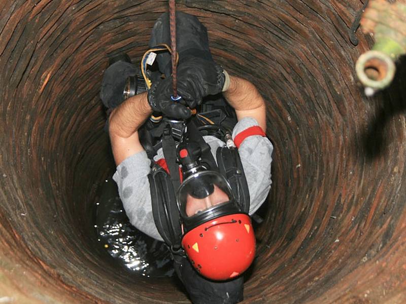 Hasič se spouští do studny na pomoc topícímu se štěněti