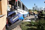 Autobus přimáčkl ke zdi rodinného domu osobní vůz.