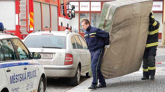 Hasiči odnášejí zpět do auta matrace, které měly zmírnit případný pád sebevraha.