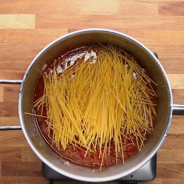 Do masové směsi přidejte špagety, které jste si předtím přelomili na polovinu, a vše zalijte 3 hrnky vody. Dejte na 15 minut vařit, aby se špagety udělaly a omáčka se zredukovala.