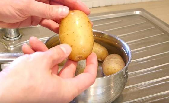 Uchopte bramboru a jemně zatlačte na slupku, ucítíte, jak vám začne pod rukama klouzat. 