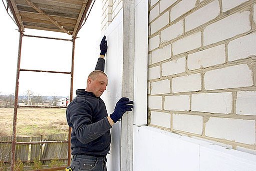 řemeslník zatepluje obvodové zdi polystyrenem