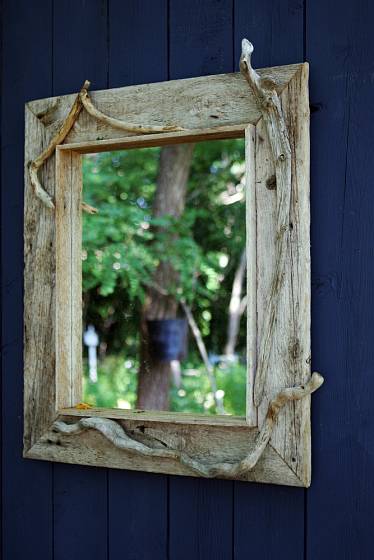 Stylově působící zrcadlo zarámované dřevem s patinou.