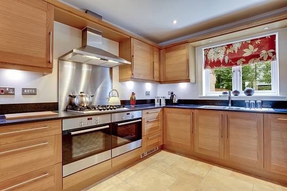 Luxusní moderní vybavená kuchyň se spotřebiči z nerezové oceli, žulovými pracovními plochami a dvěma troubami.