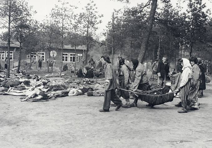 Vyčerpaní vězni v Bergen-Belsenu vynášejí mrtvá těla.