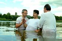 Pastor Róbert Liba (vlevo) a jeho zástupce Oldřich Gremlica křtí 14letého Tomáše v mosteckém jezeru Benedikt.