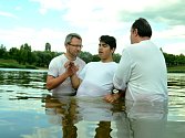 Pastor Róbert Liba (vlevo) a jeho zástupce Oldřich Gremlica křtí 14letého Tomáše v mosteckém jezeru Benedikt.
